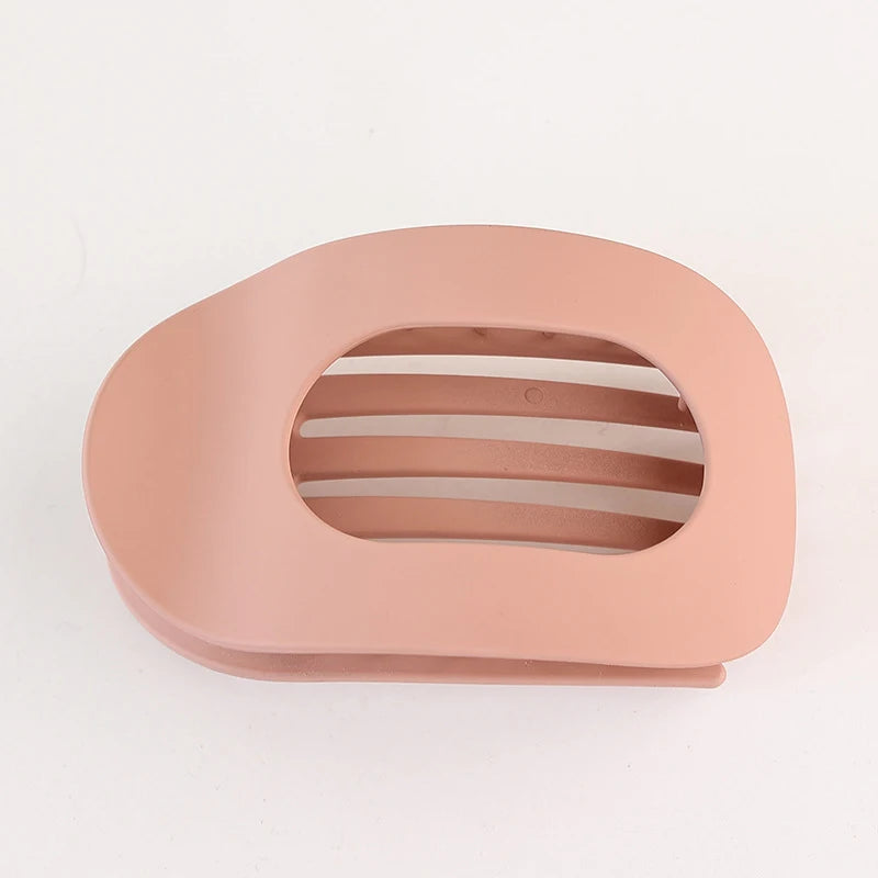 A light peach colored flat circular hair clip set with horizontal slits for hair.