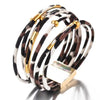 Une pile de bracelets de perles en cuir tube bohèmes léopard, avec des motifs noir et blanc et des accents dorés.