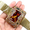 A hand holds a gold-plated swirl cuff armband watch with a square amber stone and textured gold band.