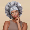 A model wearing a gray satin sleep bonnet with an Aries wrap band.