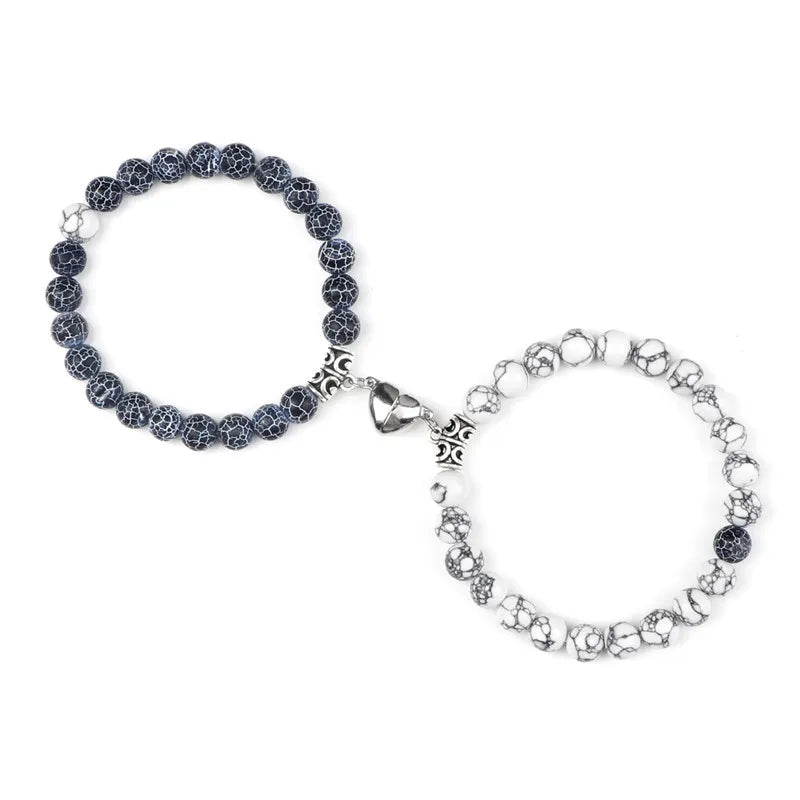 A pair of natural stone heart couple bracelets, one dark gray and one silver, displayed against a white background.