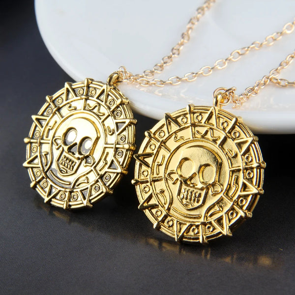 Goldener Schädel-Anhänger mit Kette auf weißem Teller.