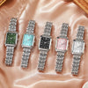Una fila de seis elegantes relojes de pulsera de cuarzo analógicos con pulseras de metal plateado sobre un fondo de satén ros