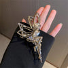 Silver rhinestone butterfly fairy angel hair clip worn on a hand against a dark background