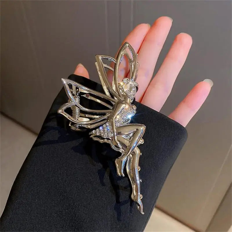 Silver rhinestone butterfly fairy angel hair clip worn on a hand against a dark background