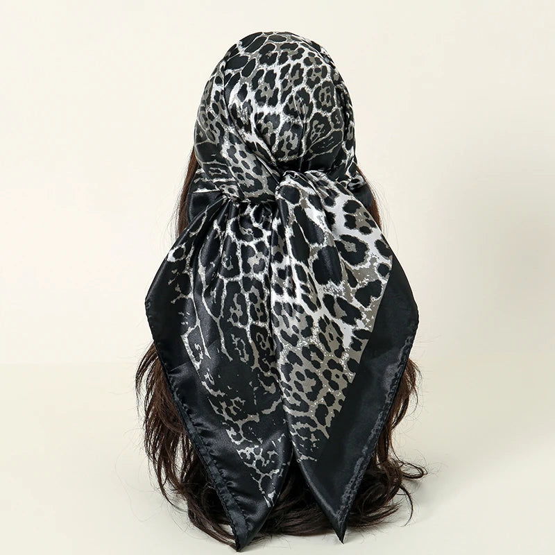 A black and gray leopard print satin silk scarf tied around dark hair.