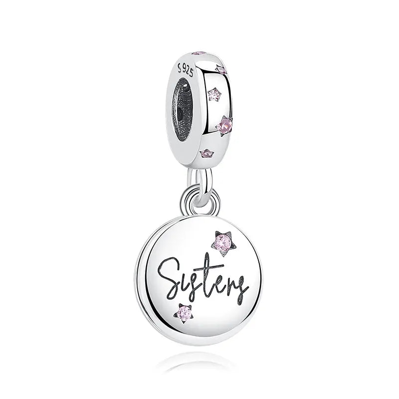 A silver family tree charm necklace featuring a circular pendant engraved with the word Sisters and small pink stones.