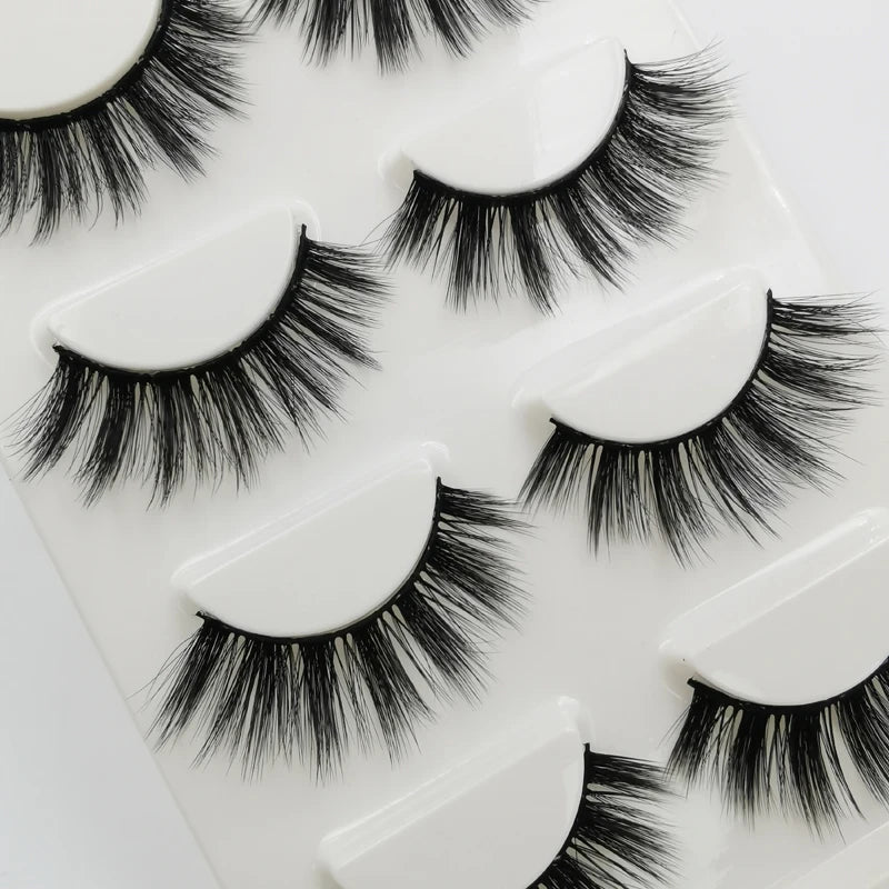 A collection of black handmade mink strip eyelashes displayed on a white plastic tray.