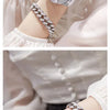 A close-up of a silver watch with a star design and a diamond bracelet on a woman's wrist.