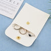 A cream-colored PU leather jewelry pouch with a snap button and several pieces of gold and silver jewelry are displayed on a 