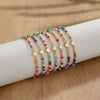 A collection of colorful resin beaded bracelets stacked on a white wrist.