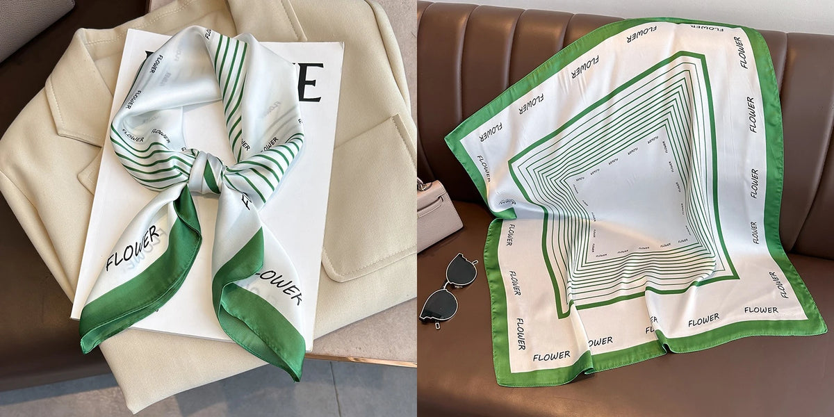 A white silk scarf with green stripes is displayed on a white card and a brown leather sofa.