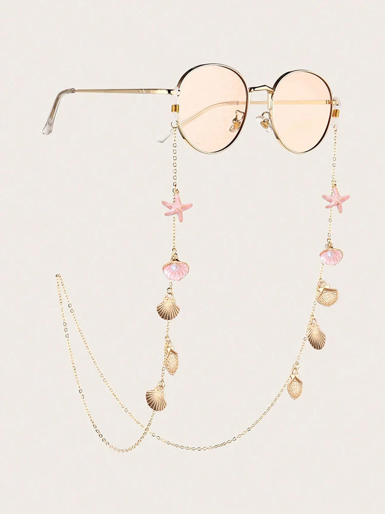 Lunettes roses claires avec montures dorées et une chaîne délicate à charms étoiles de mer et coquillage.
