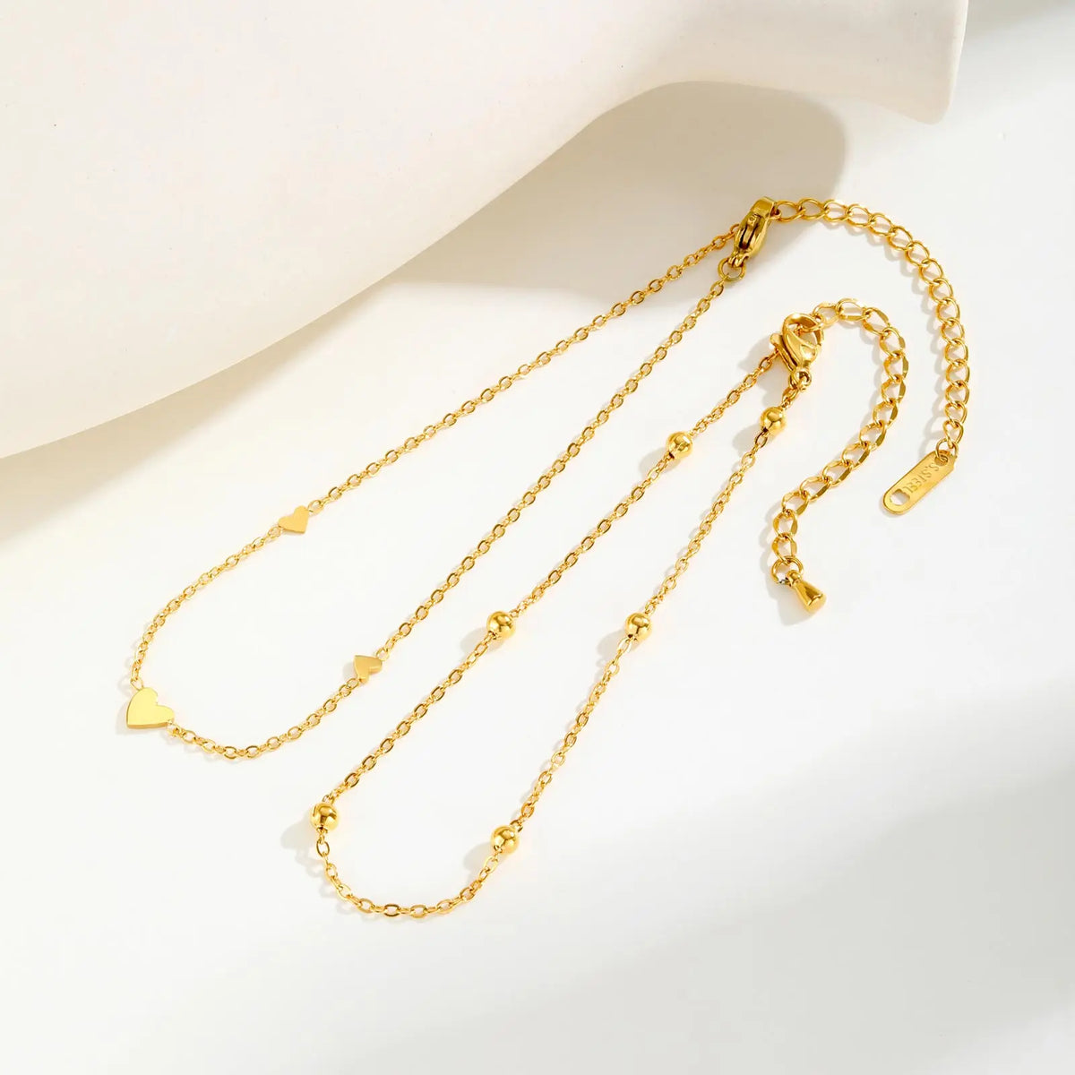 Gold stainless steel heart double chain anklet set displayed on a white background