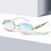 Frameless gradient sunglasses with gold accents resting on a white surface.