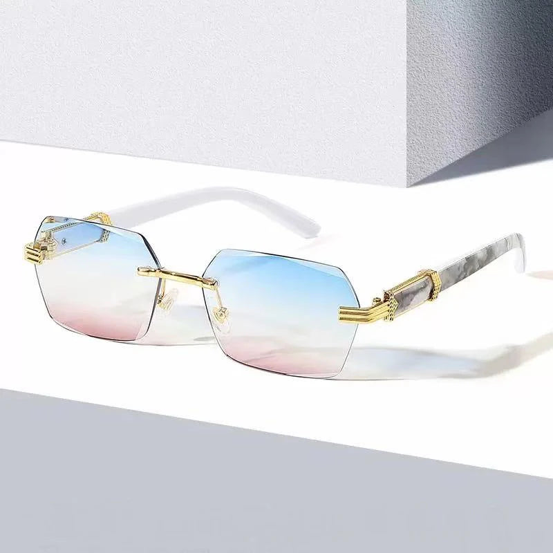 Frameless gradient sunglasses with gold accents resting on a white surface.