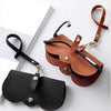 Un sac de rangement en cuir marron avec une sangle et une pochette en cuir noir, à côté d'une boîte à lunettes en cuir noir.