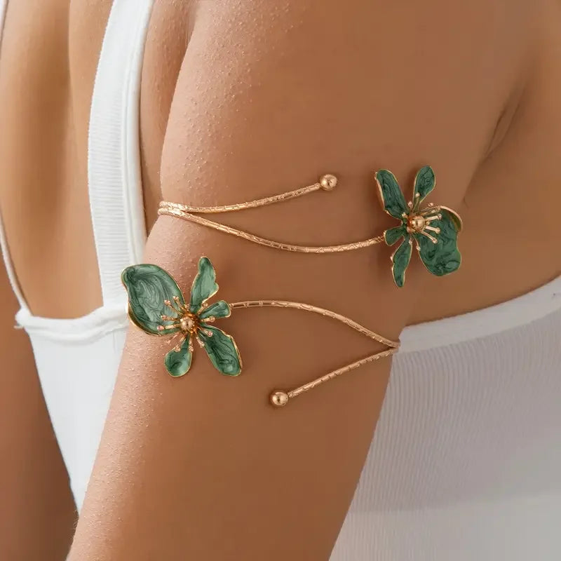 Gold floral open cuff armlet jewelry worn on a person's arm.