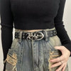 A close-up of a woman wearing a black ribbed top and distressed denim skirt with a silver Y2K hollow PU leather fashion belt.