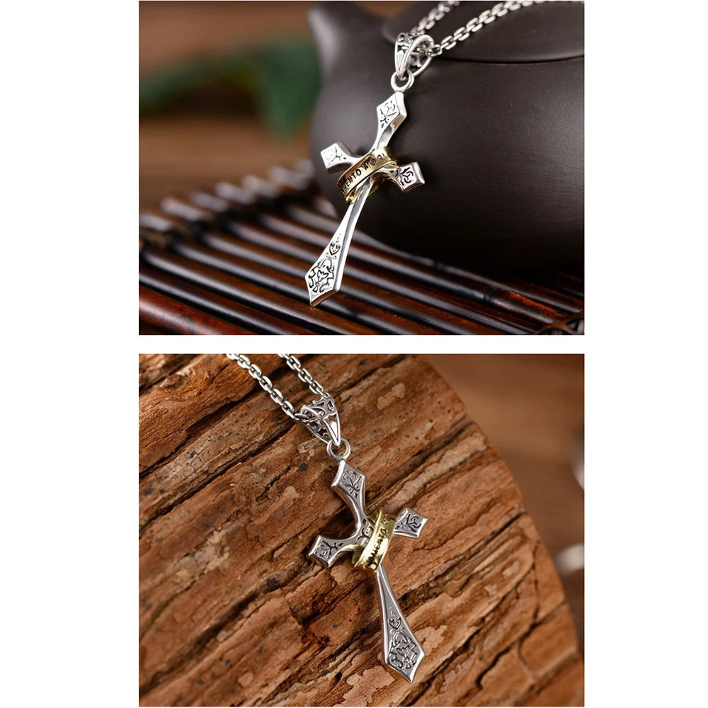 A silver stainless steel crown cross necklace displayed on a dark background and a wooden surface.