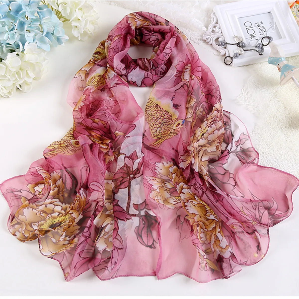 Étoffe rose transparent à motifs floraux aquarelle de roses et feuillage, présentée sur une surface blanche.