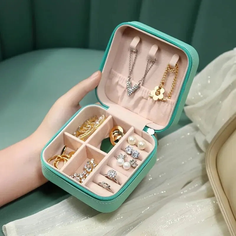 A light mint green compact leather jewelry travel organizer box with various necklaces and rings inside.