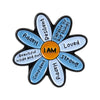 An enamel lapel pin shaped like a flower with words such as Resilient Happy Loved and Strong inside