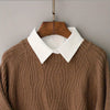 A brown knitted sweater with a white collar displayed on a wooden hanger.