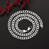 Ensemble collier et bracelet en chaîne argentée enroulé sur une surface sombre avec des feuillages rouges.