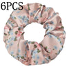 Un set de seis gomas de tela satinada rosas con estampado floral de flores azules y rosas.
