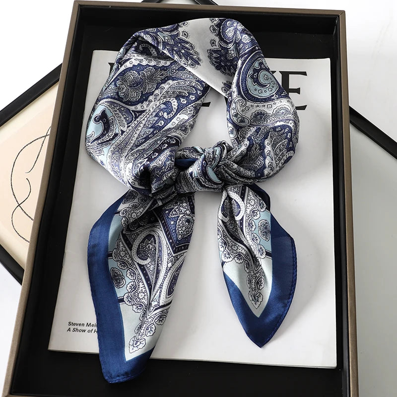 A dark blue and white patterned silk scarf tied in a knot displayed in a black frame.
