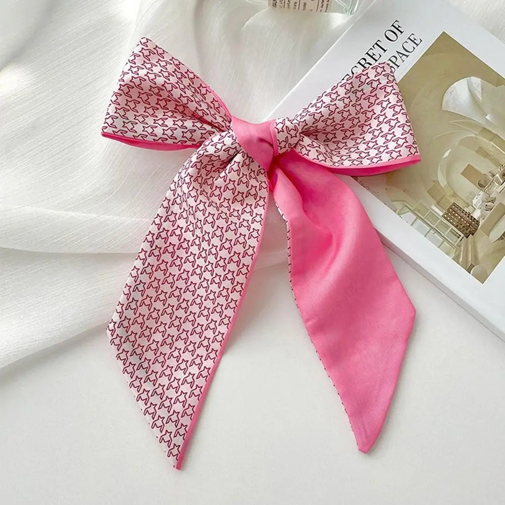 Diadema de flor de seda rosa atada en un lazo, apoyada sobre una superficie blanca.