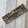 Diadema deportiva impermeable de leopardo negro y dorado sobre una superficie de madera clara.
