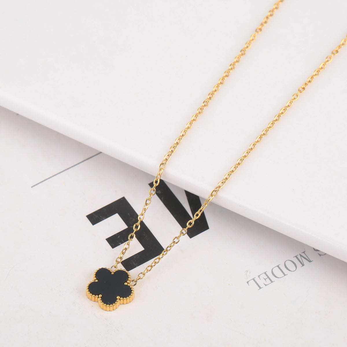Una delicada pulsera de flores de planta de acero inoxidable chapado en oro, mostrada sobre un fondo blanco.