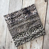 Una pila de bandanas deportivas impermeables de estampado de leopardo sobre una superficie de madera desgastada.