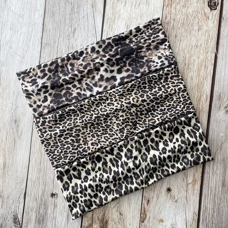 Una pila de bandanas deportivas impermeables de estampado de leopardo sobre una superficie de madera desgastada.