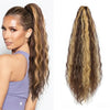 Une femme montre de longues extensions de cheveux bouclés, coiffées en queue de cheval haute et en ondulations lâches.