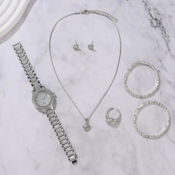 A collection of elegant quartz crystal jewelry including a necklace, earrings, and several rings displayed on a white marble 