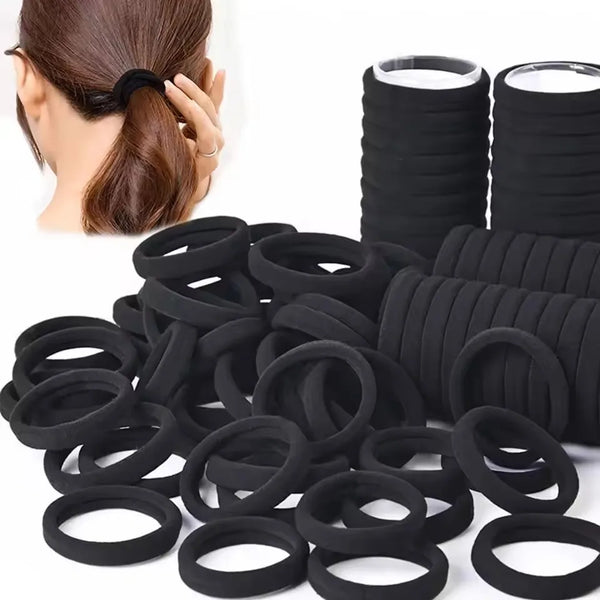 A pile of black elastic hair ties for ponytails and buns, with a woman's hair in a ponytail visible.