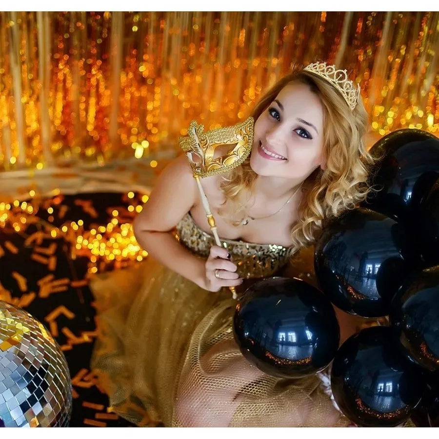 A smiling girl wearing a gold tiara crown and a golden sash, posing in a lavish, warm-toned setting.
