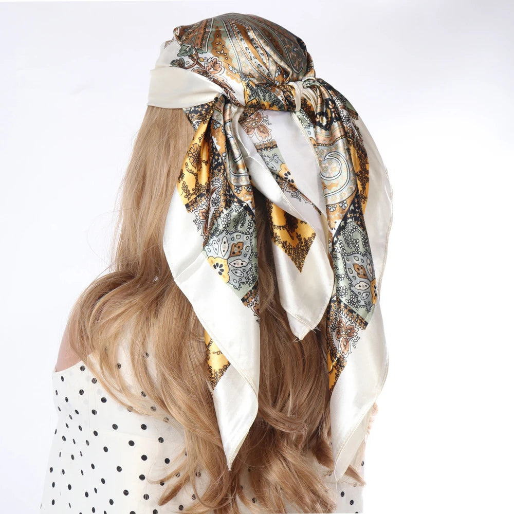 Langes blondes Haar einer Frau, gebunden mit einem gemusterten Seideschal als Boho-Halstuch.