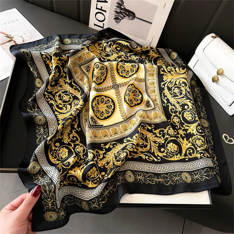 A black and gold patterned silk scarf or square shawl with intricate baroque and geometric designs.