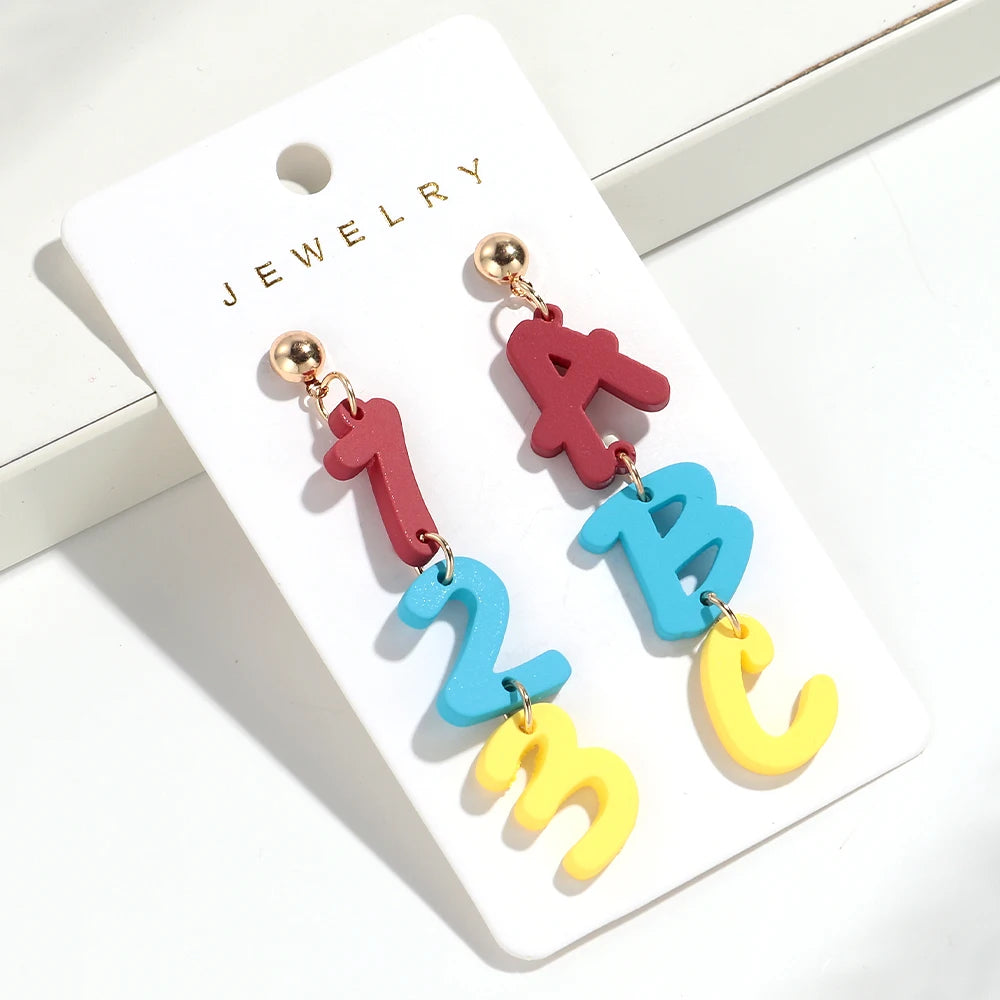 Un par de pendientes colgantes con forma de 1 y la letra B en tonos rojos, azules y amarillos.