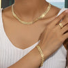 A close-up of a gold-toned dainty necklace and bracelet set with small heart charms worn by a woman.