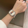 A close-up of a hand wearing a square beaded watch strap with a white face and a gold-toned bracelet.