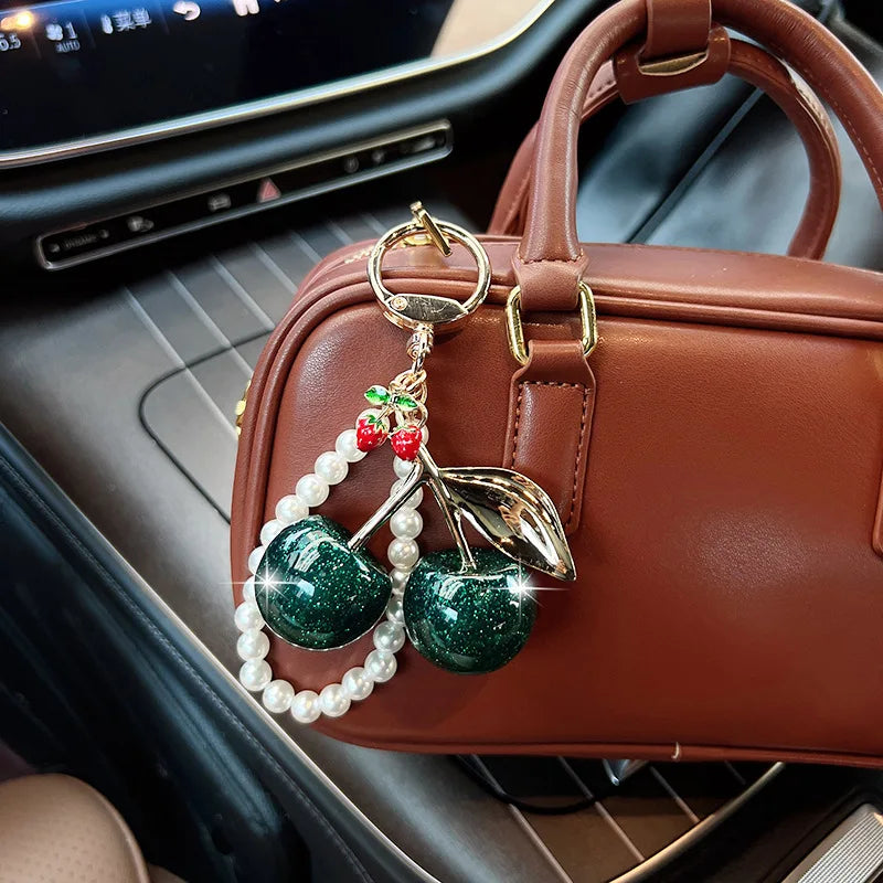 A brown leather handbag with a pearl bead key chain decoration featuring a green apple charm.