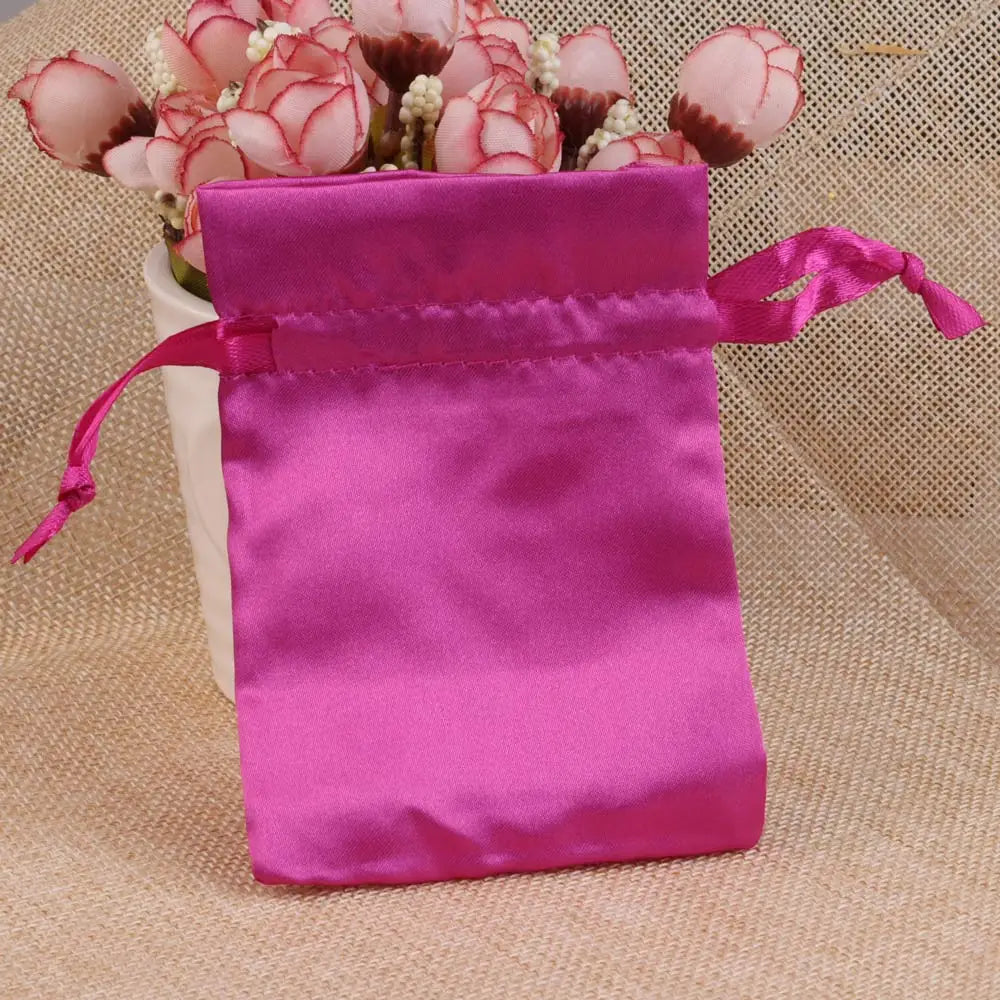 A vibrant pink satin drawstring pouch filled with pink and white floral elements.