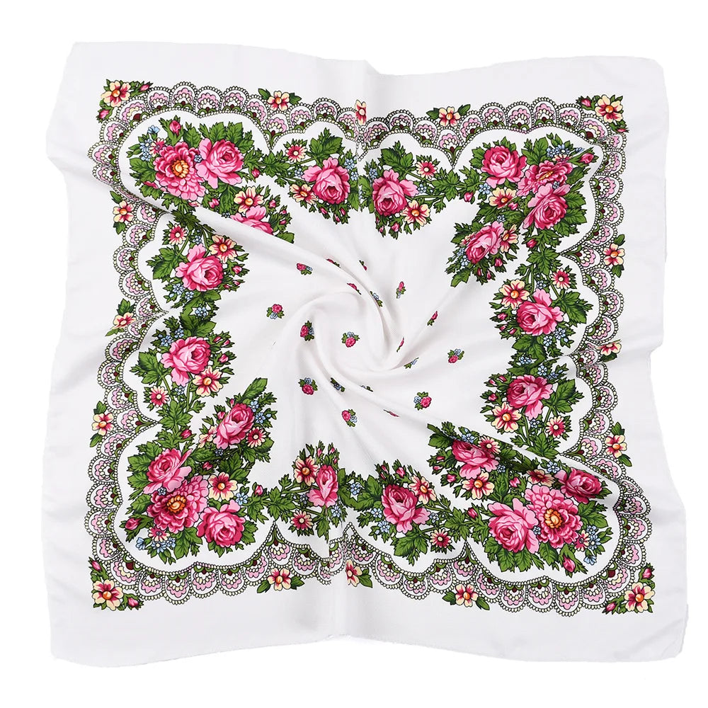A white square scarf featuring a luxury floral print with pink and green roses and foliage.