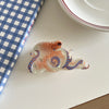 Pince à cheveux en forme d'octopus translucide et coloré avec des motifs tourbillonnants de rose, blanc et bleu.