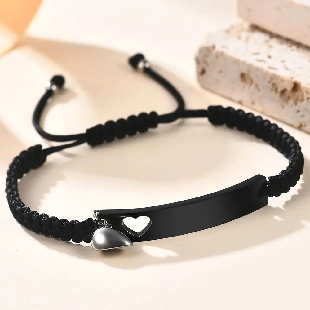 Schwarzes Perlenarmband mit silbernem Herzcharm auf weißem Untergrund neben Seife.